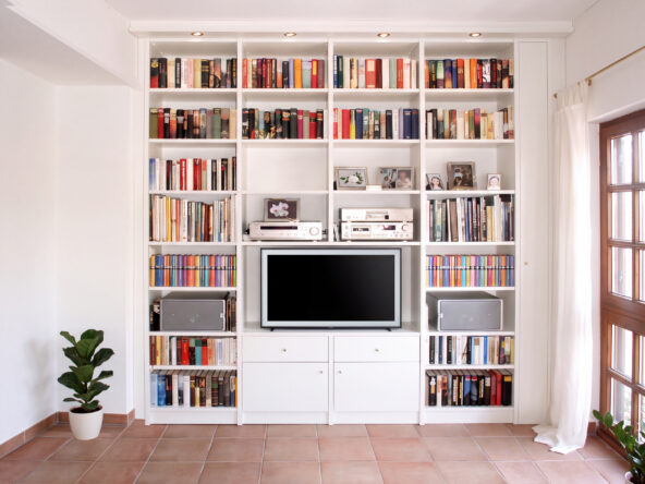 Bücherregal mit TV-Fach in der Mitte. Darunter sind Türen und Schubladen.