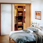 Ein begehbarer Kleiderschrank mit Glasschiebetüren mit Holzrahmen