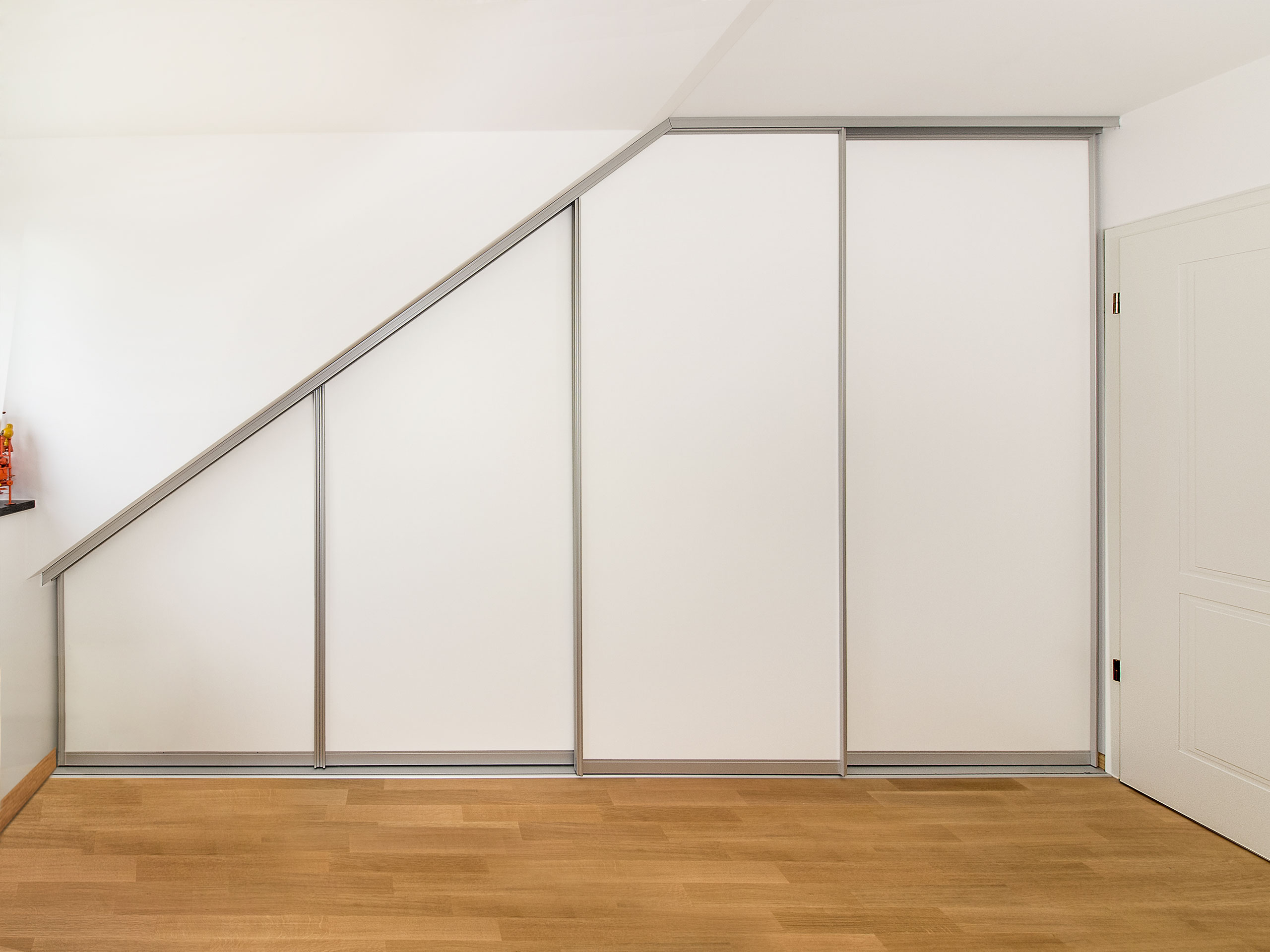 Schiebetürschrank in der Dachschräge in zeitlos modernem Design. Die Aluminiumrahmen und die weißen Türfüllungen sind optisch zurückhaltend. Der Schrank dient als Kleiderschrank in der Dachschräge.