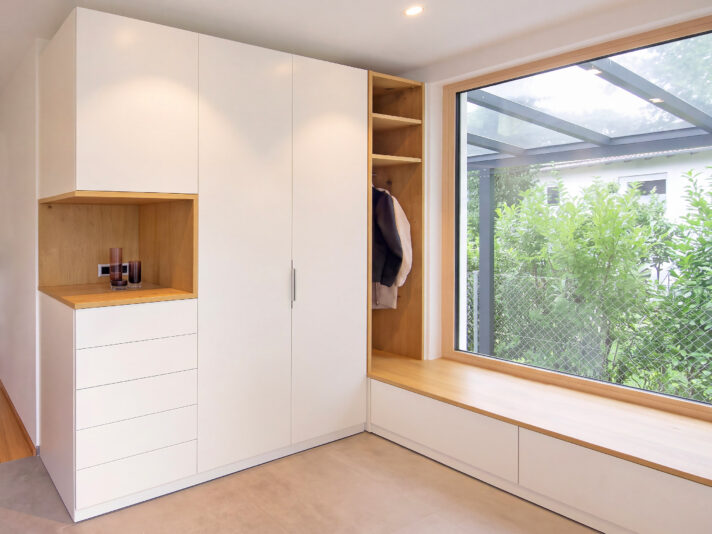 weiß beschichtete Einbaugarderobe mit Sitzbank in Diele. Bild wurde mit KI retuschiert.