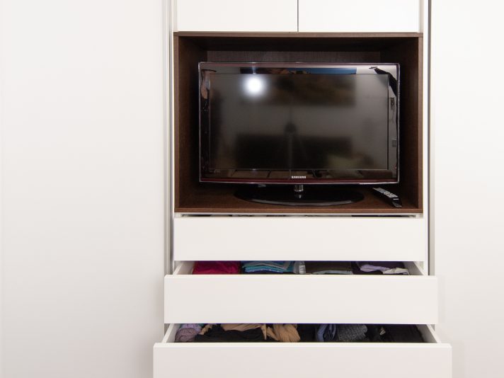 Eine in dunklem Holz abgesetzte Nische bietet Platz für den Fernseher. Durch das dunkle Holz fällt der Fernseher weniger auf.