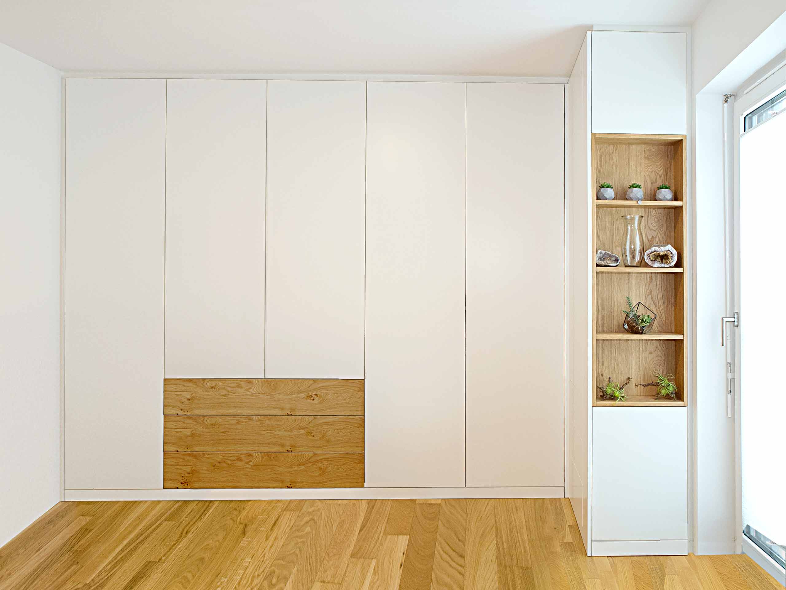 Griffloser Einbauschrank in Weiß und Asteiche. Der Schrank ist passgenau gefertigt und zur Wand und zur Decke komplett verblendet. Die Ecklösung und der offene Design-Regaleinsatz in Asteiche Echtholz geben dieser Einrichtung das gewisse Etwas. Die grifflosen Türen und Schubladen unterstreichen den modernen Charakter.