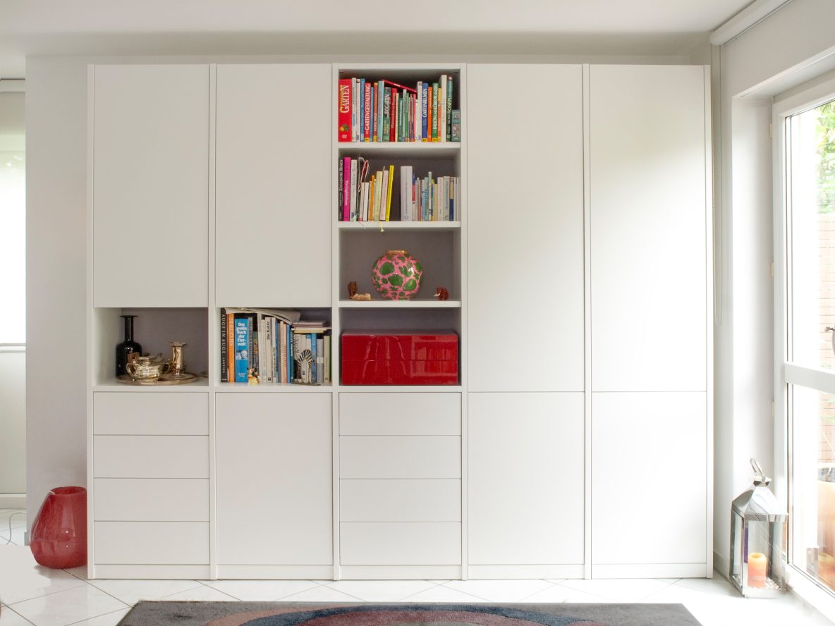 Moderne, weiße Wohnwand. Diel vielen Türen und Schubladen bieten viel geschlossenen Stauraum. In der Mitte wird das Design durch offene Regale aufgelockert.