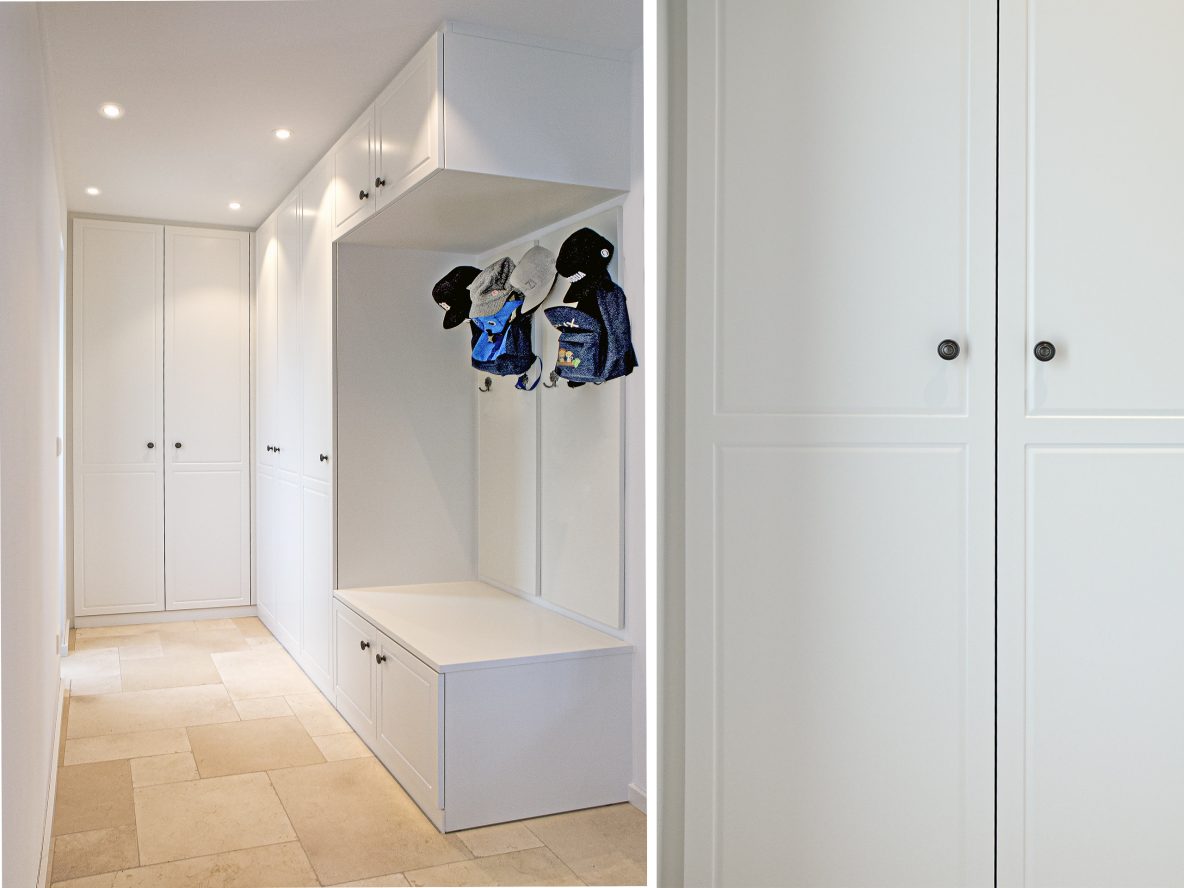 Weißer Einbauschrank im Flur mit offener Garderobe, Sitzbank und Hängeschrank.
