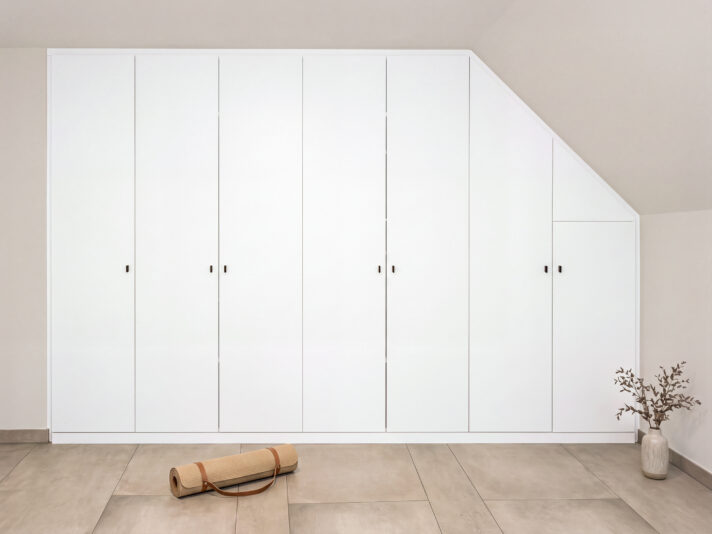 Siebentüriger Schrank in der Dachschräge, auf der echten Seite abgeschrägt. Das Bild wurde mit KI bearbeitet.