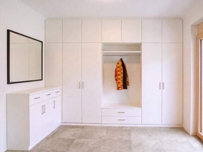 Großer, weißer Garderobenschrank mit weißer Rückwand. Bild wurde von KI retuschiert.