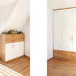 Eine weiß beschichtete Kommode und ein Einbauschrank in einem Schlafzimmer in Dachschräge. Bild wurde von KI retuschiert.